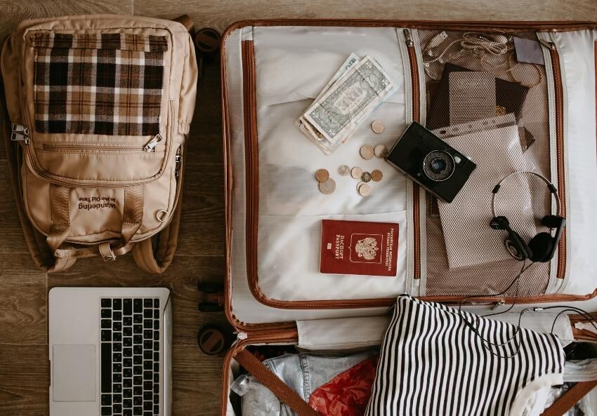 Je nach Bedarf gehören auch Ladekabel, Laptop und Fotoapparat mit ins Gepäck Gepackter Reisekoffer