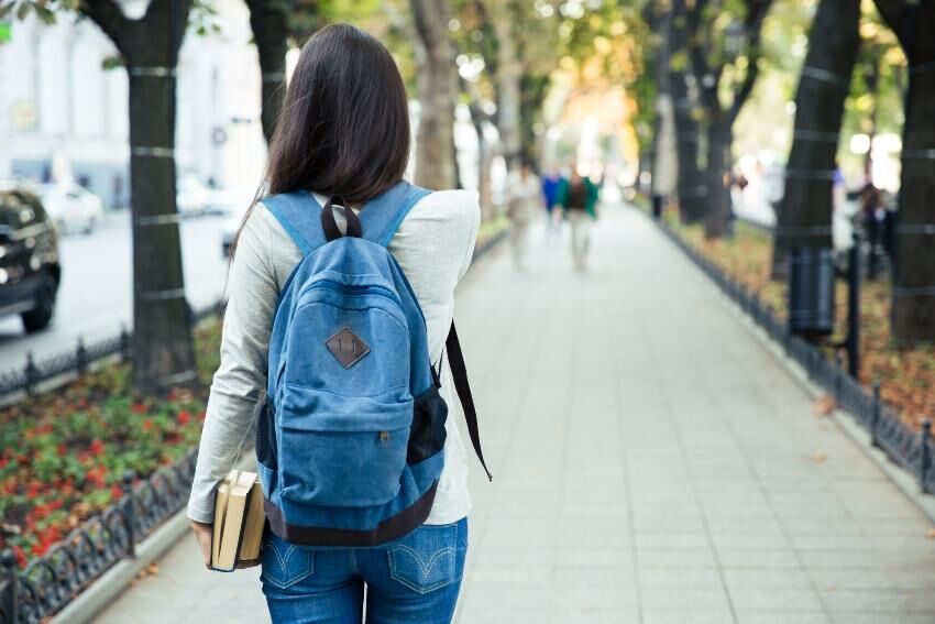 Ein Rucksack muss immer gut sitzen - ob für die Schule, die Uni oder zum Wandern Junge Frau mit einem Rucksack
