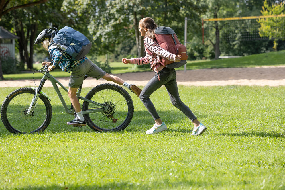 Ein Kind mit Helm und Schulranzen fährt allein auf einem Fahrradweg.