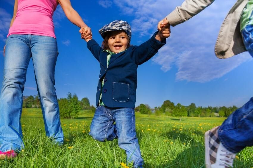 Kind spielt mit Eltern im Gras - Letztes Kindergartenjahr sinnvoll nutzen