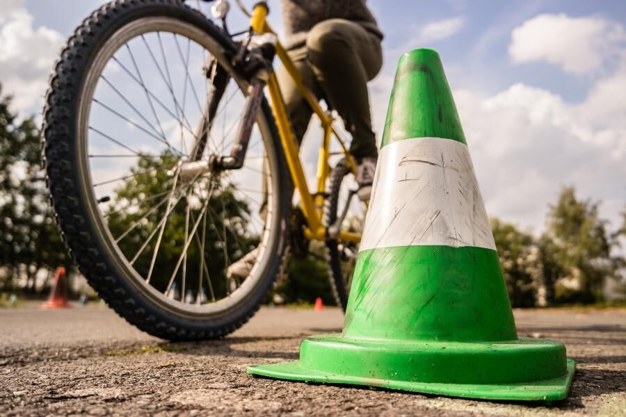 Kinder üben mit Fahrrädern auf einem Verkehrsübungsplatz mit Ampeln und Schildern.