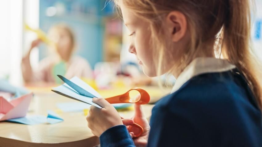 Das Basteln mit Schere und Papier fördert die Feinmotorik und ist auch für andere Schulfächer förderlich Mädchen bastelt mit Schere und Papier