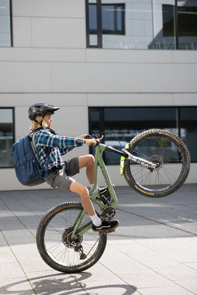 Ein Vater läuft lachend neben seinem Sohn her, der gerade Fahrradfahren lernt.