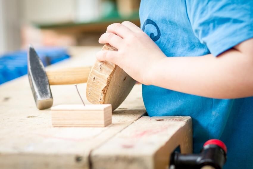 Kinder lernen dabei auch direkt, das Werkzeug wieder wegzuräumen und für Sicherheit zu sorgen Kind arbeitet mit Holz und Hammer