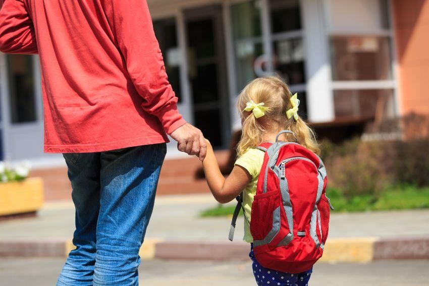 Entscheidend ist das Gesamtgewicht aus Schulranzen und Inhalt Junges Mädchen mit Schulranzen, begleitet von Elternteil - Schulranzen ist nicht zu schwer